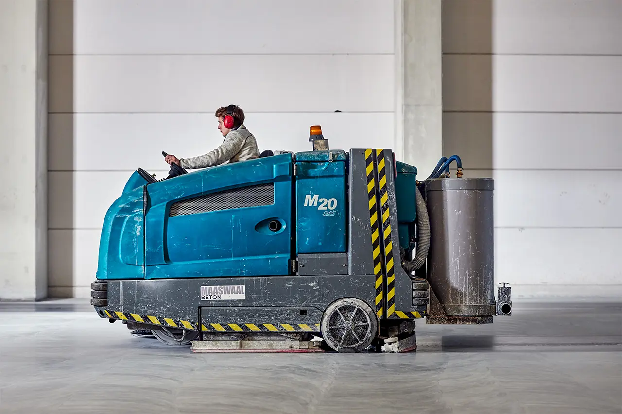 Dweilen van een gepolijste betonvloer met schrobmachine