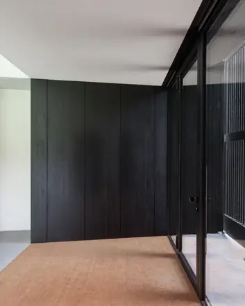 Entree met donkere houten panelen, glazen deuren en betonnen vloer, moderne stijl