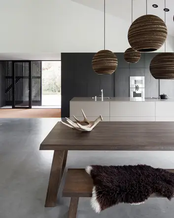 Moderne keuken met gevlinderde betonvloer, houten tafel, hangende lampen, witte muren en natuurlijke elementen