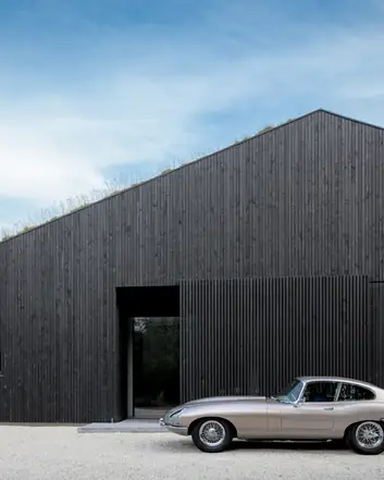 Zwart houten gevel met groen dak, moderne architectuur, betonvloer entree buiten, klassieke auto vooropgesteld