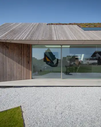 Modern huis met beton terras, groen dak en grote glazen wanden, strakke architectuur, ruime tuin