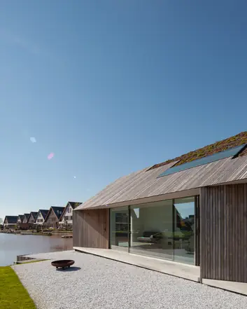 Moderne woning met beton terras, groen dak en uitzicht op water