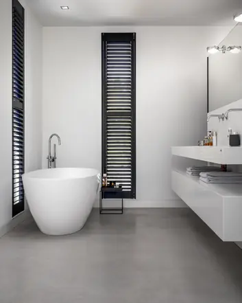 Modern badkamerinterieur met woonbetonvloer, witte badkuip en minimalistische designelementen