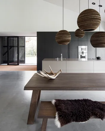 Moderne keuken met gevlinderde betonvloer, houten tafel, hangende lampen, witte muren en natuurlijke elementen