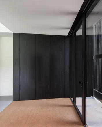 Entree met donkere houten panelen, glazen deuren en betonnen vloer, moderne stijl