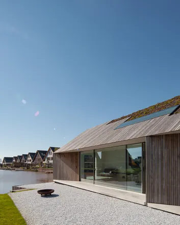 Moderne woning met beton terras, groen dak en uitzicht op water