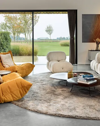 Modern interieur met betonvloer, comfortabele meubels en uitzicht op groen landschap