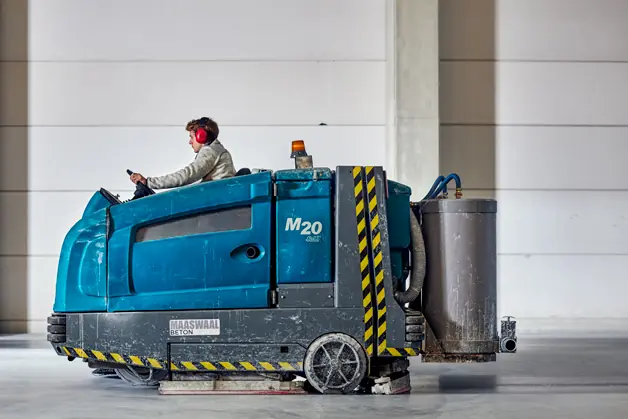 Dweilen van een gepolijste betonvloer met schrobmachine