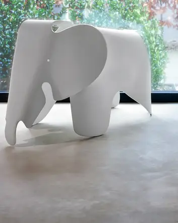Een witte olifant op een gevlinderde betonvloer
