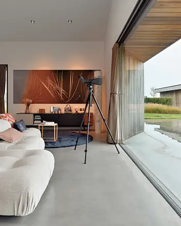 Woonkamer met gevlinderde betonvloer, moderne meubels en uitzicht op gevlinderde betonvloer buiten