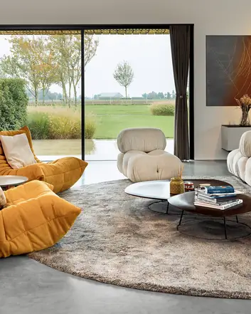 Modern interieur met betonvloer, comfortabele meubels en uitzicht op groen landschap